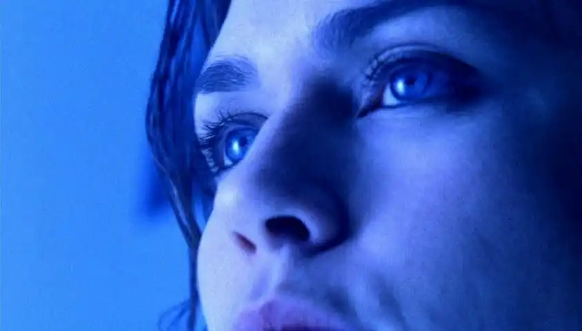 A close-up of a woman’s face illuminated in blue