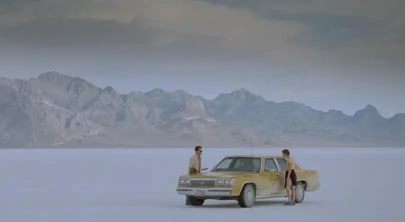 A man and a woman around a car in a completely empty plain